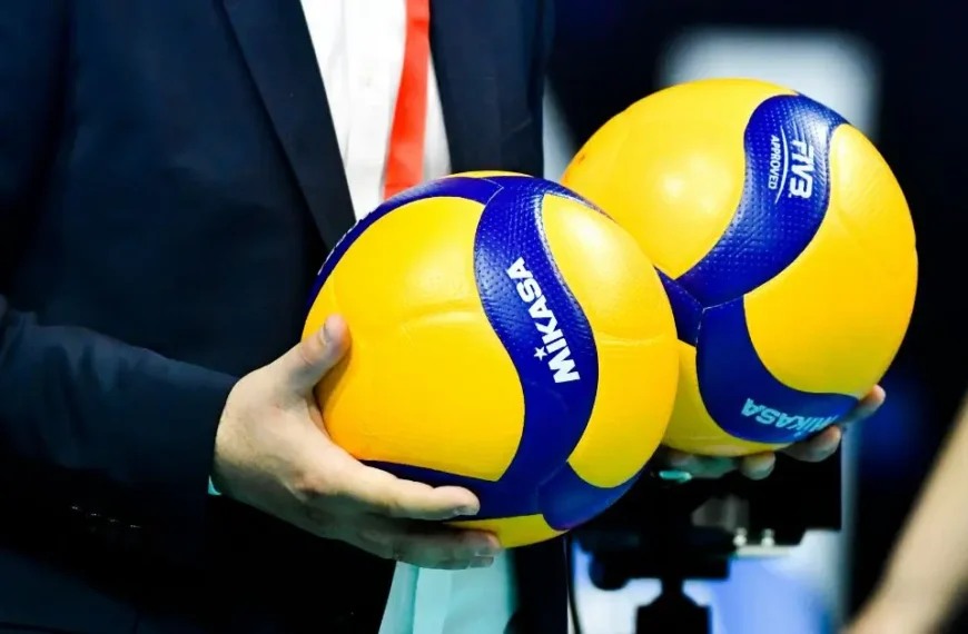 How to Keep Score in Volleyball: A referee holding two Volleyballs in his hand